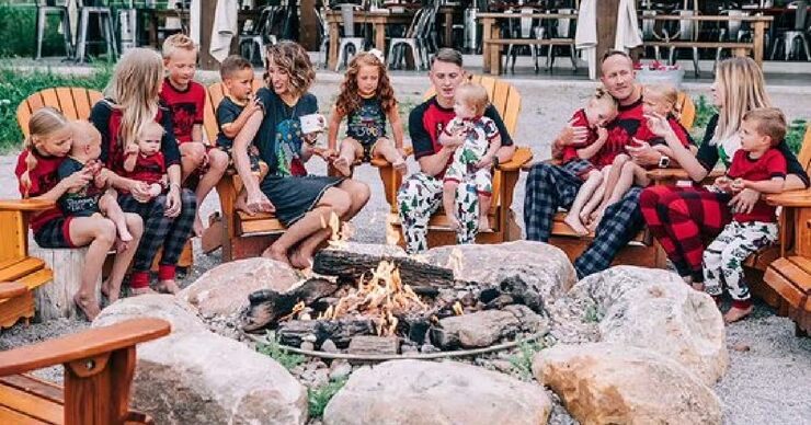 family sitting around a campfire wearing camping themed family matching pajamas