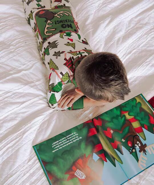 child laying down on a bed reading a moose themed book