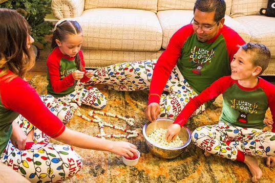 family wearing matching Christmas reindeer pajamas while making a popcorn garland