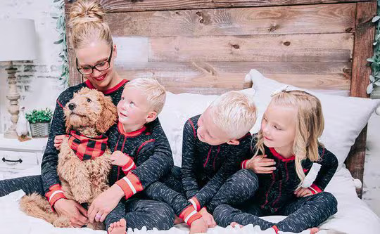 dog wearing a plaid bandana sitting with family on bed
