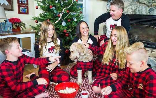 family sitting in front of a Christmas tree wearing matching family pajamas