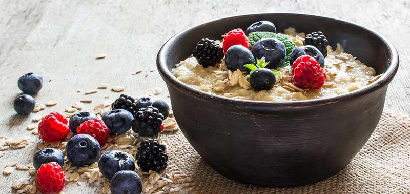 a bowl of oatmeal topped with black, red and blue berries
