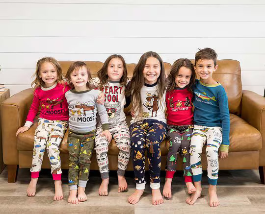 six kids wearing matching LazyOne pajamas sitting side by side on a small couch