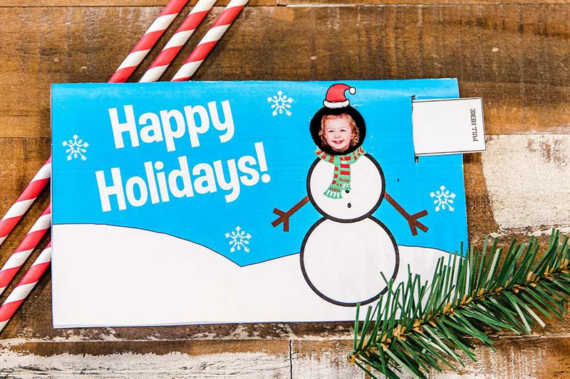 Christmas card with a sliding tab showing a child's face in the place of a snowman head