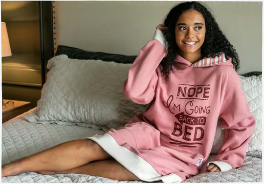 woman laying down wearing a pink sleep hoodie